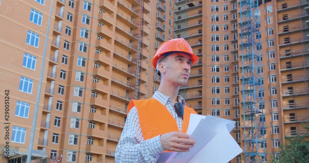 Wall mural portrait of construction specialist in orange helmet and safety vest against big building