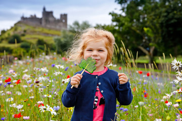 Cute toddler girl with Irish cloverleaf lollipop with Rock of Cashel castle on background. Happy...
