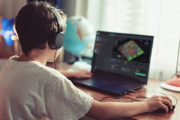 Little dependent gamer kid playing mass multiplayer game on laptop at home © sakkmesterke
