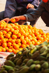 Two Vietnamese selects oranges on the roadside.