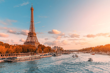 De belangrijkste attractie van Parijs en heel Europa is de Eiffeltoren in de stralen van de ondergaande zon aan de oever van de rivier de Seine met toeristische cruiseschepen