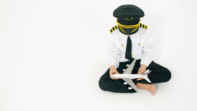 Boy wearing pilot's uniform plays with toy commercial airplane