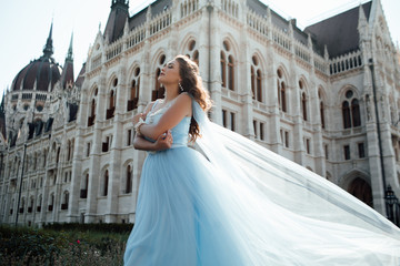 Attractive stylish woman walking near building in fashionable outfit waving dress wind luxary style. Female fashion. Beautiful woman with professional make up and hairstyle