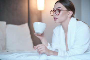 girl in a bathrobe drinks morning coffee