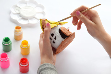 Making toys with your own hands, paints a clay house with gouache. Indoors creative leisure for...
