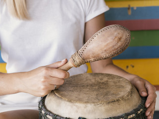 Young person playing percussion instruments near multicolored wall