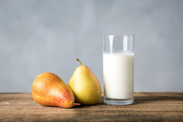 two pears and a glass of kefir on a wooden table on a gray background