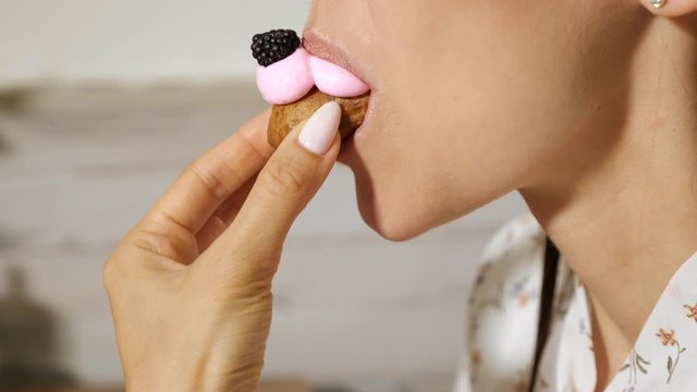 pretty young woman eats beautiful tasty eclair with cream, close up