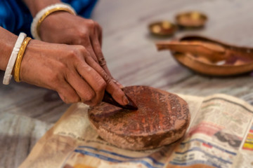 Fototapeta na wymiar Person Rubbing Sandalwood. Indian woman rubbing sandalwood or chandan on a stone for puja or pooja preparation. Background image for hindu culture, tradition or Durga Puja with copy space.