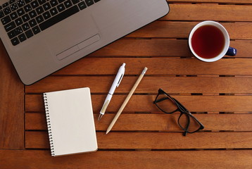 notebook with pen, cup, glasses and all important properties on wooden table