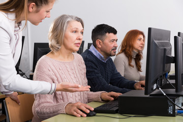 Businesswoman helping to coworkers, pointing at computer monitor