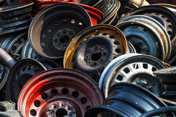 Old hubcaps with no logo. Some rusty, some not. In a heap and abandoned. Red one in front.