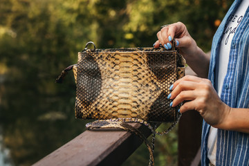 Stylish woman with snakeskin handbag outdoors.