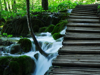 Obraz premium Plitvice, Kroatien: Ruhiger Wasserstrom unter einer Holzbrücke
