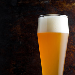 Close - up of traditional full glass of unfiltered wheat beer on brown old dark background