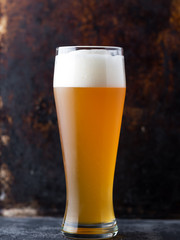 Close - up of traditional full glass of unfiltered wheat beer on brown old dark background