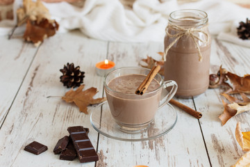 Hot chocolate cacao drink with marshmallows and cinnamon on wooden background.