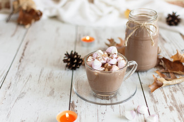 Hot chocolate cacao drink with marshmallows and cinnamon on wooden background.