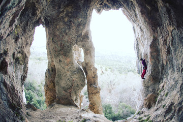A man climbs the rock against of a mountain landscape. The athlete trains on a natural relief....