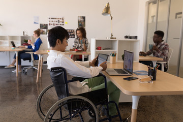 Disabled male executive using digital tablet at desk
