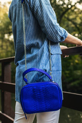 Stylish woman with snakeskin handbag outdoors.