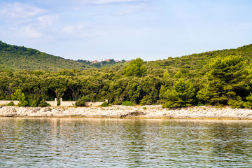 View of the rocky shore, wooded. In the distance you can see a small Croatian village