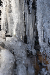 Natural background with icicles on a stone rock.