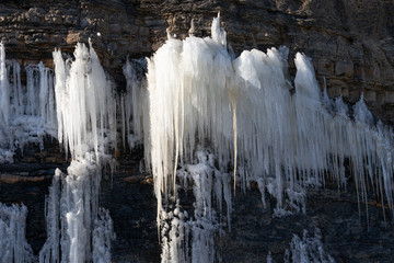 Natural background with icicles on a stone rock.