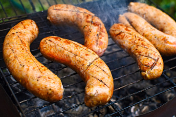 Appetizing grilled bavarian sausages on grate during cooking.