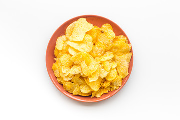 Potato chips in bowl ready to eat on white background top view