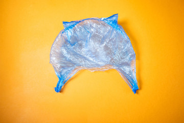 Cellophane tblue bag lies on a bright orange background. The minimalist image is suitable as a background, there is a place for text or logo. Top view