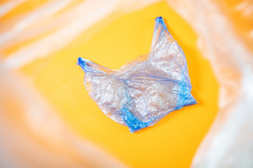 Cellophane blue bag lies on a bright orange background. The minimalist image is suitable as a background, there is a place for text or logo. Top view