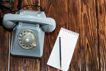 vintage grey phone, writing pad on wooden background close-up, top view