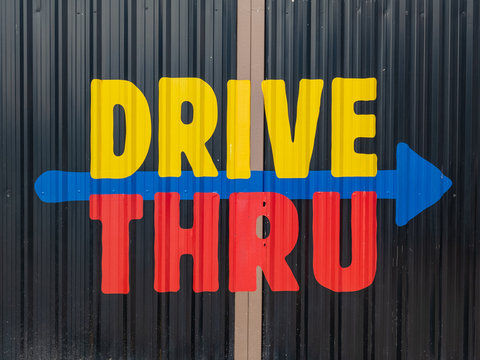 Colorful drive thru sign in red, blue and yellow on metal sheet background
