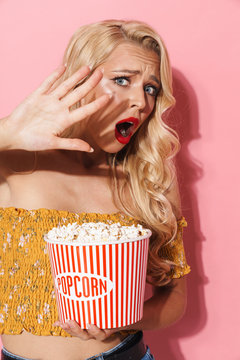 Image of frightened young woman screaming and holding popcorn bucket