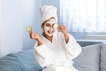 Young woman with cleansing mask on her face at home. Skin care. Woman aplying beauty mask,close up. So beautiful. Close-up of girl with beauty mask on her face looking in mirror.