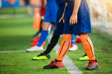 Kid soccer players standing over white line on green artificial turf ready to training and start...