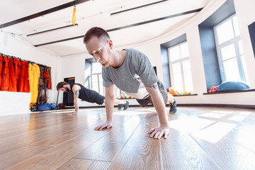 Two friends men in good physical shape doing workout together in the gym. Concept of team spirit and joint visits to the hall for support. Side view of two young sportman in sportswear doing plank