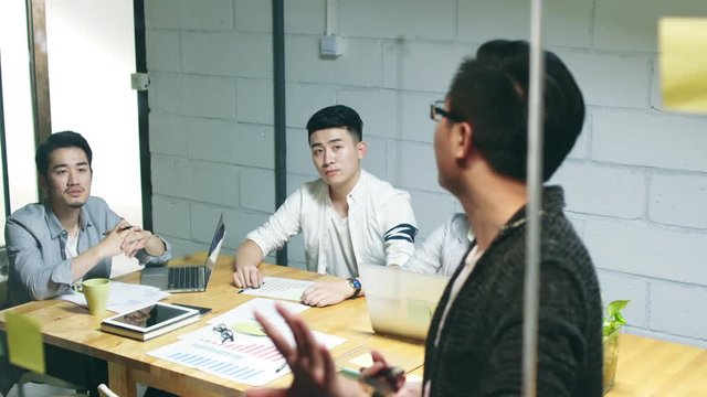 group of young asian entrepreneurs discussing business in company meeting room