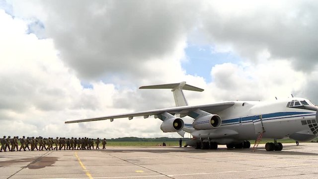 Military paratroopers systems go to the plane on the background of the cloud, preparing to Board the plane