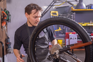 Service, repair, bike and people concept - Mechanic repairing a mountain bike in a workshop