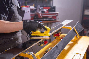 Repair, service and people concept - a man repairing the ski by rubbing a paraffin