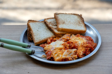 Portion of shakshuka on a plate. Middle eastern traditional dish with fried eggs, tomatoes, bell pepper and vegetables