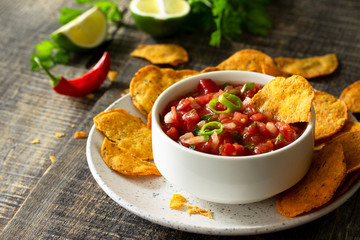 Tasty mexican nachos chips in bowl with salsa dip on wooden table. Free space for your text.