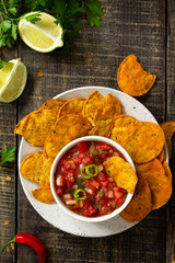 Tasty mexican nachos chips in bowl with salsa dip on wooden table. Top view flat lay. Free space for your text.