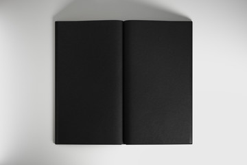 Open book with blank black sheets at light background, copyspace.