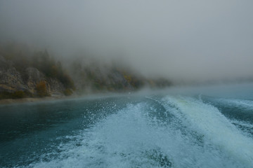 Walk on a mountain lake on a boat in the fog in the autumn. Boat fog autumn