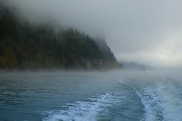 Walk on the Norwegian lake on a boat in the autumn in the fog. Wake of the boat