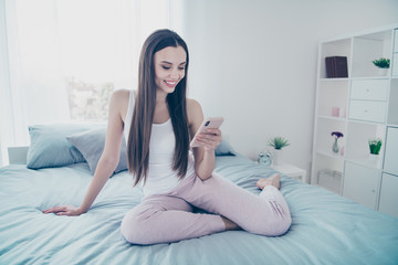 Close-up portrait of her she nice beautiful attractive lovely charming cute sweet feminine cheerful cheery girl using 5g app sitting on sheets in white light interior room house indoors