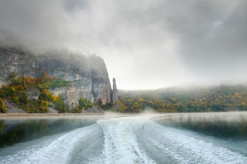 Walk on the Norwegian lake on a boat in the autumn in the fog. Wake of the boat